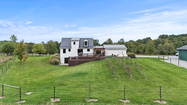 back of house featuring a lawn, a wooden deck, and a rural view