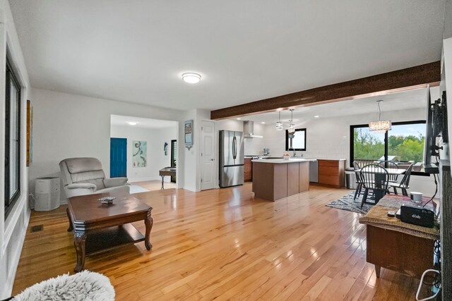 living room featuring a notable chandelier, light hardwood / wood-style flooring, and beam ceiling