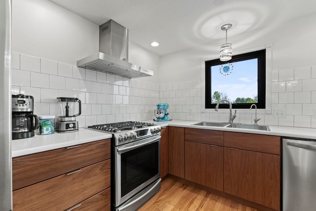 kitchen with light wood-type flooring, tasteful backsplash, sink, wall chimney range hood, and stainless steel appliances