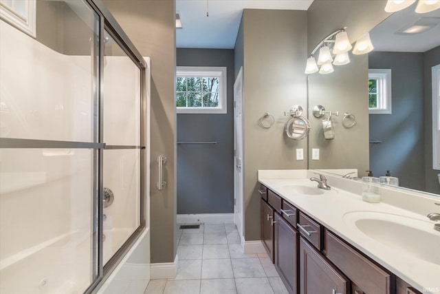 full bath featuring tile patterned floors, enclosed tub / shower combo, double vanity, and a sink