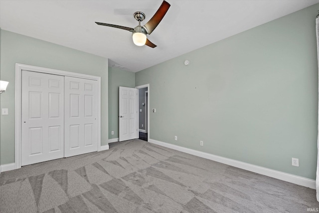 unfurnished bedroom with a closet, carpet flooring, baseboards, and a ceiling fan