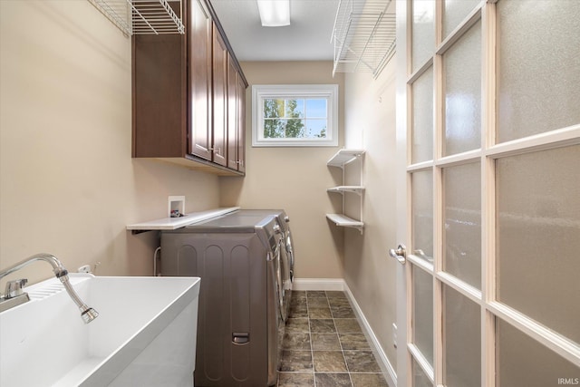 laundry area featuring baseboards, washing machine and dryer, a sink, and cabinet space