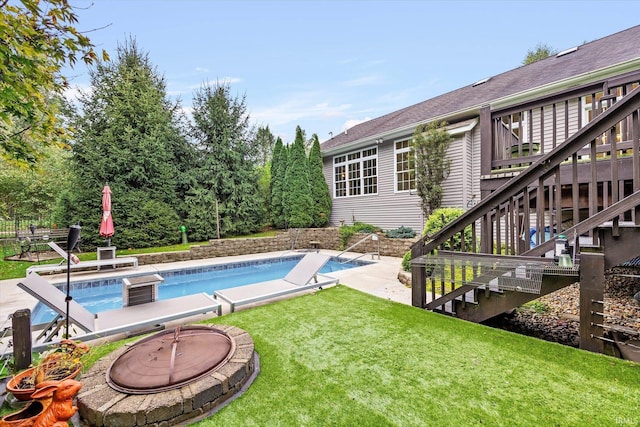 pool with an outdoor fire pit, a patio, a yard, and stairway