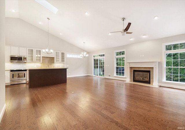 unfurnished living room featuring a skylight, high vaulted ceiling, a fireplace with flush hearth, and dark wood finished floors