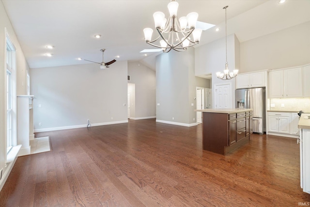 kitchen featuring dark wood finished floors, a kitchen island, light countertops, stainless steel fridge, and open floor plan