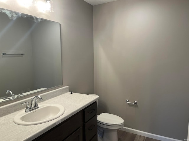 bathroom with wood-type flooring, vanity, and toilet