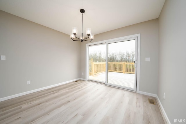 unfurnished room with light hardwood / wood-style floors and an inviting chandelier