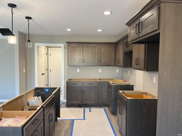 kitchen featuring decorative light fixtures, dark brown cabinetry, a textured ceiling, and light hardwood / wood-style flooring