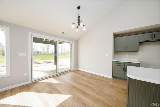 kitchen with light hardwood / wood-style flooring, a wealth of natural light, high vaulted ceiling, and hanging light fixtures