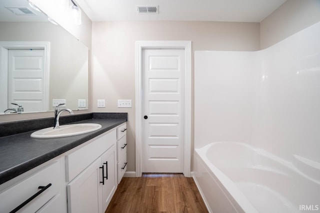 bathroom featuring wood-type flooring, vanity, and a bathing tub