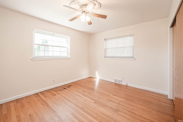 unfurnished bedroom with ceiling fan, a closet, light hardwood / wood-style floors, and multiple windows