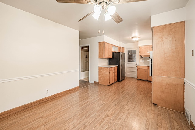 kitchen featuring stainless steel refrigerator, light hardwood / wood-style floors, backsplash, and ceiling fan