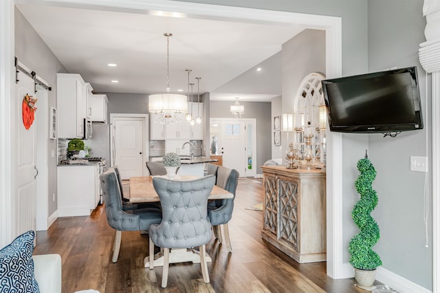 dining space featuring an inviting chandelier, sink, a barn door, and dark hardwood / wood-style flooring