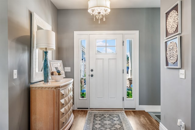 entryway with wood-type flooring and a chandelier