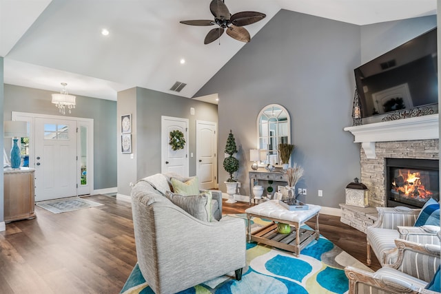 living room featuring ceiling fan with notable chandelier, a fireplace, dark hardwood / wood-style flooring, and high vaulted ceiling