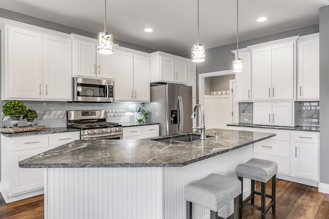 kitchen featuring white cabinetry, dark wood-type flooring, stainless steel appliances, a kitchen island with sink, and sink