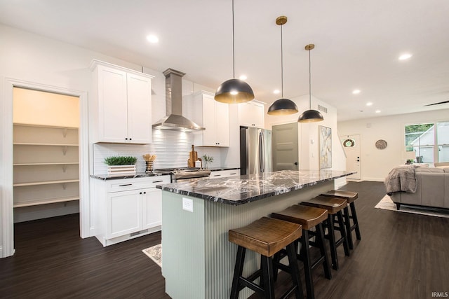 kitchen featuring dark hardwood / wood-style flooring, wall chimney range hood, stainless steel appliances, and white cabinets