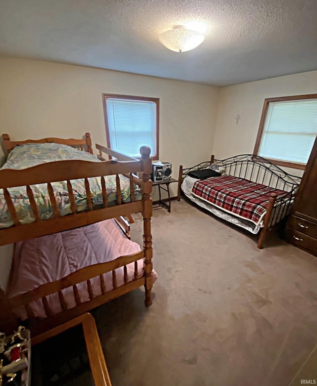 bedroom with carpet, multiple windows, and a textured ceiling