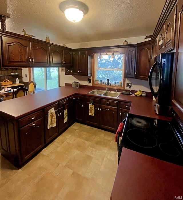 kitchen featuring dark brown cabinetry, a textured ceiling, sink, and kitchen peninsula