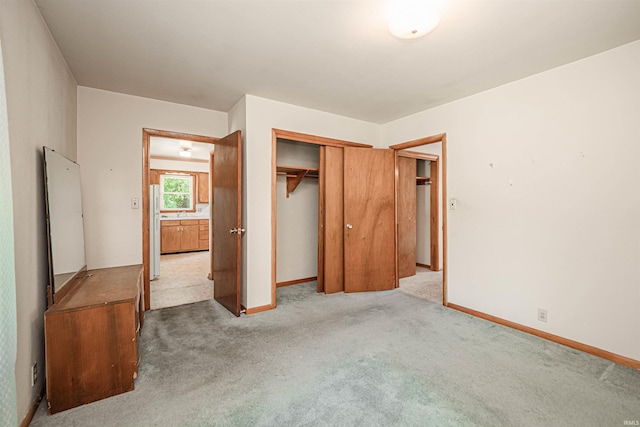 unfurnished bedroom featuring white fridge, light colored carpet, and a closet