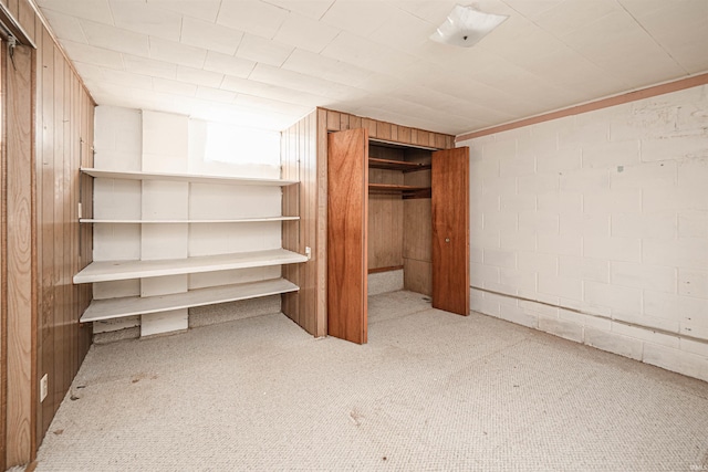 unfurnished bedroom with light colored carpet and wood walls