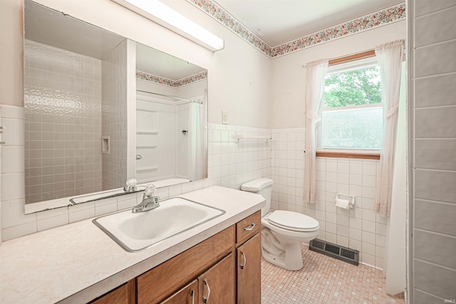 bathroom with vanity, tile patterned floors, walk in shower, tile walls, and toilet