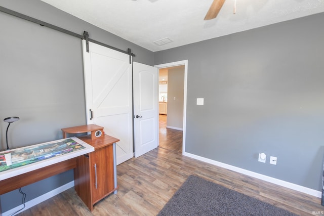 office area with ceiling fan, dark hardwood / wood-style floors, and a barn door