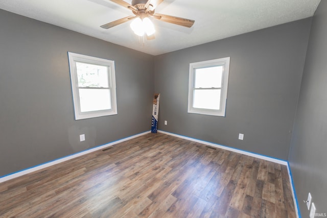 unfurnished room with ceiling fan, plenty of natural light, and dark hardwood / wood-style flooring