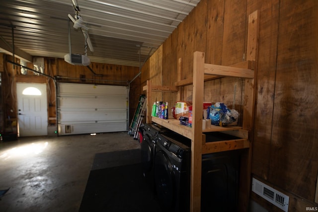 garage with a garage door opener, wood walls, and independent washer and dryer