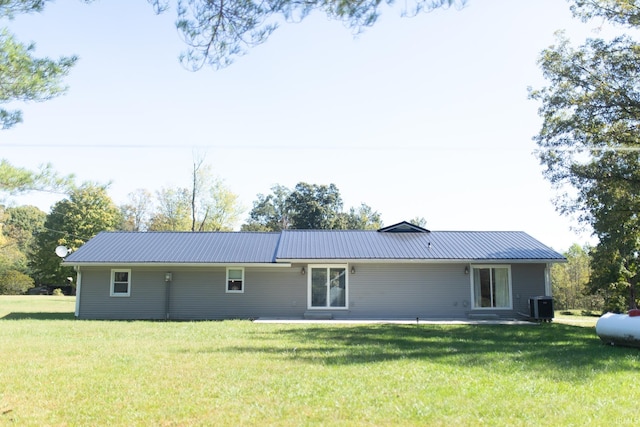 rear view of property featuring central AC unit and a lawn