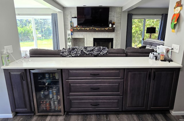 interior space featuring dark brown cabinets, beverage cooler, dark hardwood / wood-style floors, and a brick fireplace