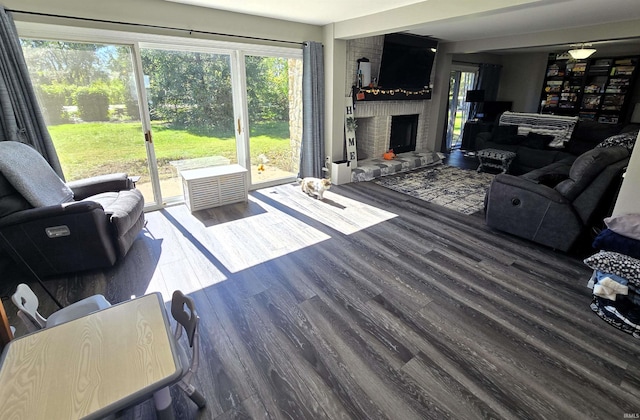 living room with dark wood-type flooring and a brick fireplace