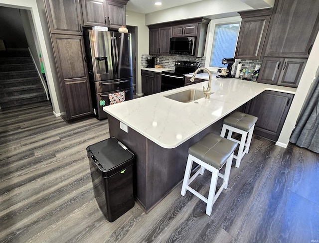 kitchen with sink, dark hardwood / wood-style floors, stainless steel fridge, black / electric stove, and a breakfast bar area