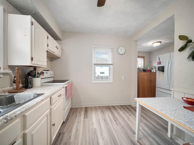 kitchen featuring a textured ceiling, light hardwood / wood-style floors, white appliances, and white cabinetry