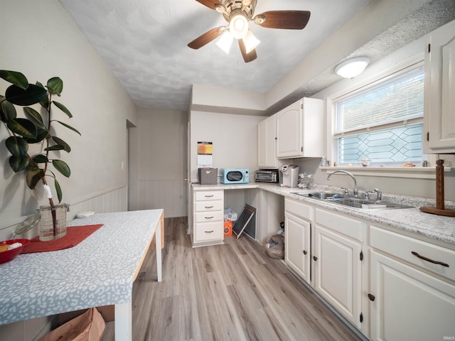 kitchen featuring ceiling fan, sink, a textured ceiling, white cabinetry, and light hardwood / wood-style floors