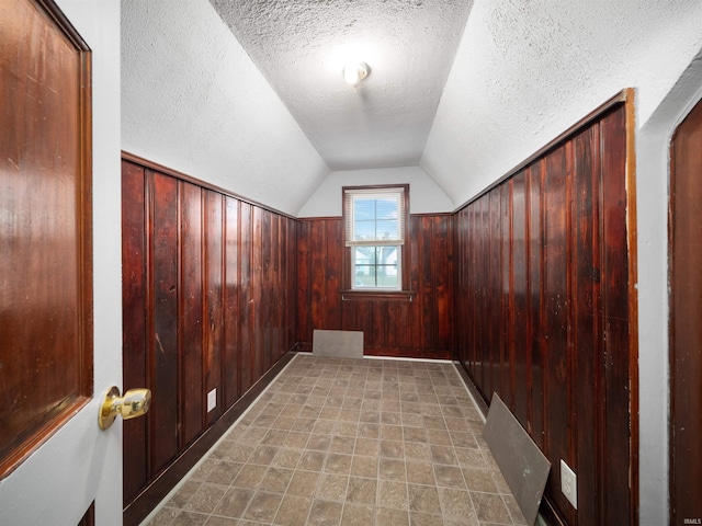 bonus room featuring wood walls, a textured ceiling, and vaulted ceiling