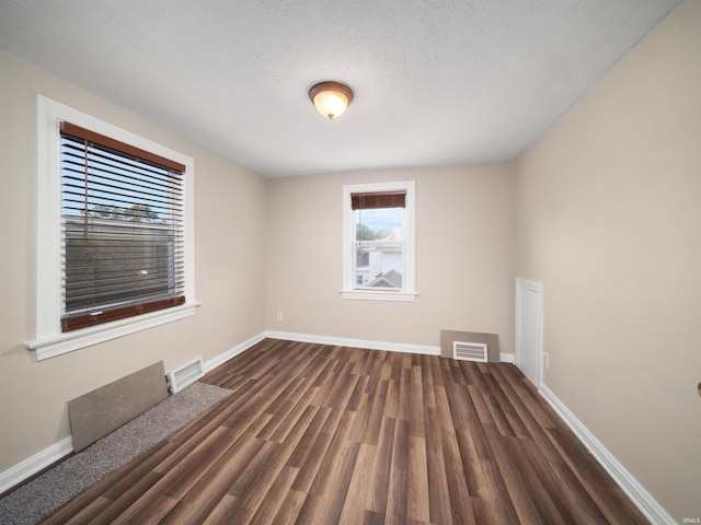 unfurnished room featuring a textured ceiling and dark hardwood / wood-style floors