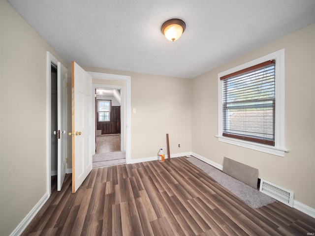 spare room featuring a textured ceiling and dark hardwood / wood-style flooring