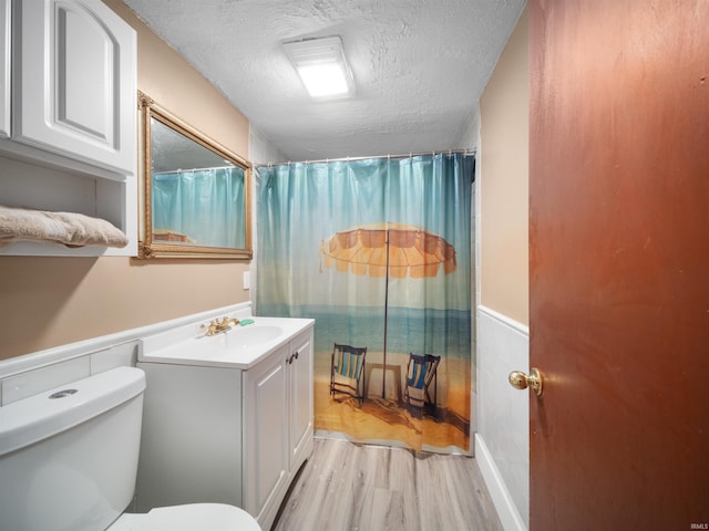 bathroom with wood-type flooring, a textured ceiling, vanity, and toilet