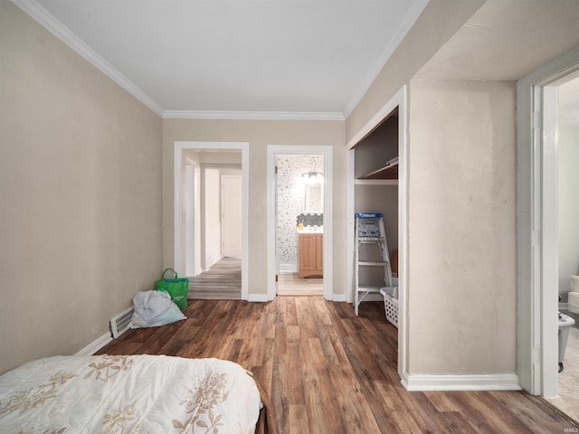 bedroom with ornamental molding, connected bathroom, and dark hardwood / wood-style flooring