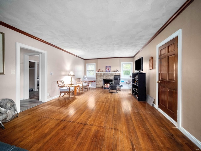 unfurnished living room with wood-type flooring, a stone fireplace, and crown molding