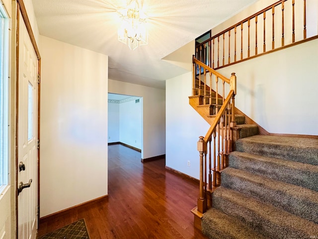 stairs with hardwood / wood-style flooring and a chandelier