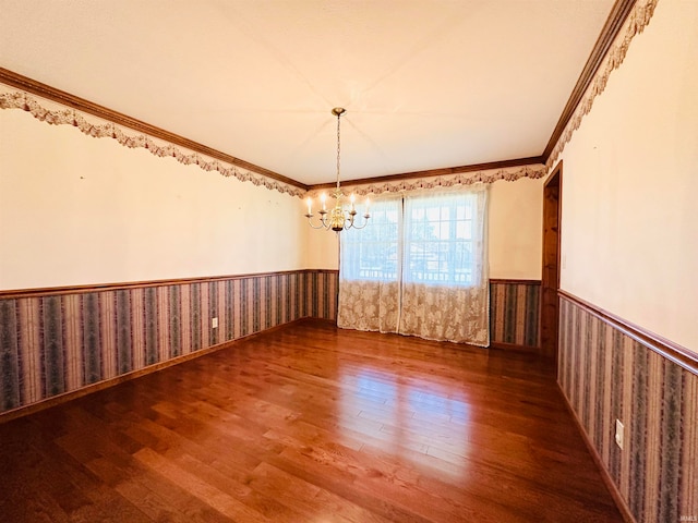 empty room featuring ornamental molding, dark hardwood / wood-style flooring, and a chandelier