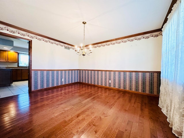 unfurnished room with ornamental molding, a chandelier, and hardwood / wood-style floors