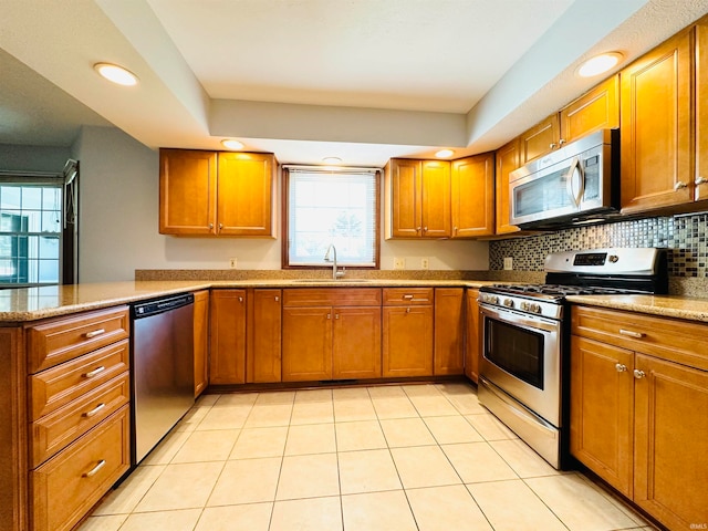 kitchen with light stone counters, light tile patterned flooring, sink, appliances with stainless steel finishes, and decorative backsplash