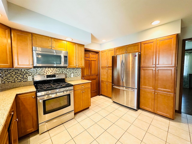 kitchen featuring light stone countertops, light tile patterned floors, appliances with stainless steel finishes, and tasteful backsplash