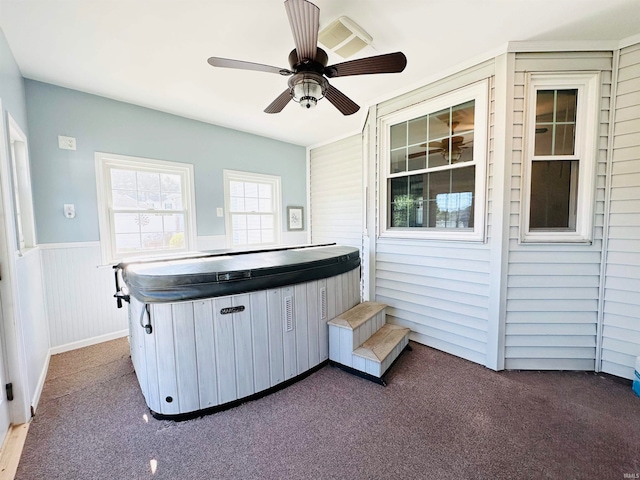 misc room featuring carpet flooring, wood walls, a hot tub, and ceiling fan