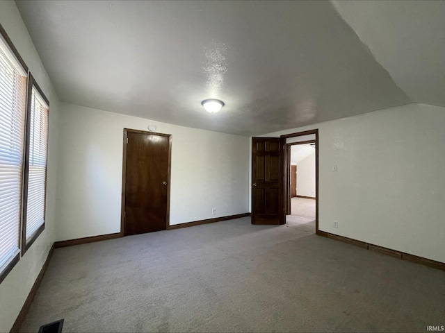 carpeted spare room with vaulted ceiling