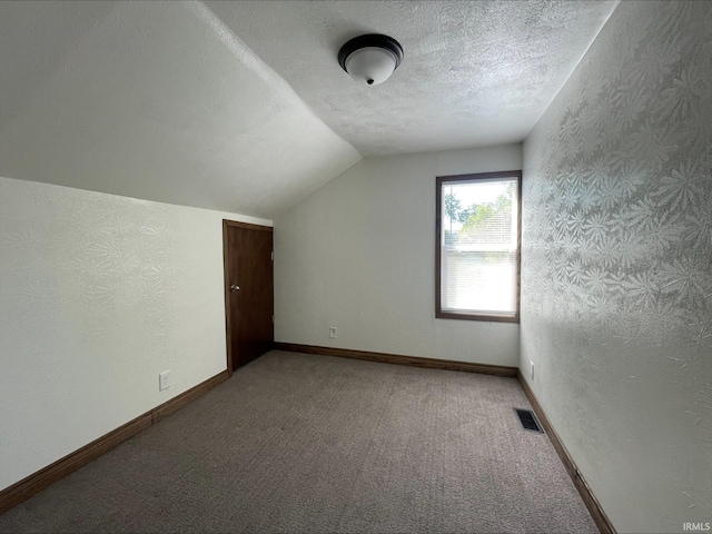 bonus room featuring a textured ceiling, vaulted ceiling, and carpet