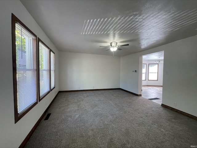 spare room with ceiling fan with notable chandelier and carpet flooring